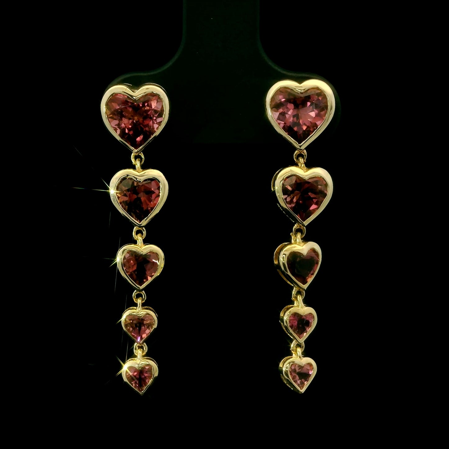 Heart-shaped earrings with red gemstones on a black background
